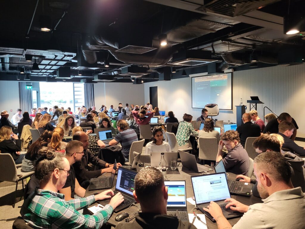 The MKO team at an AI training day - the image shows a room of people sat around circular tables, each with a laptop in front of them