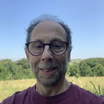 A photo of David Feige CEcol FCIEEM smiling at the camera and wearing a dark purple tshirt